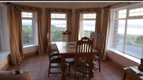a dining room with a table and chairs and windows at Ballylawn Lodge in Letterkenny