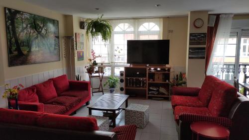 a living room with red couches and a flat screen tv at Pensión Residencia Miñones in Bayo Grande