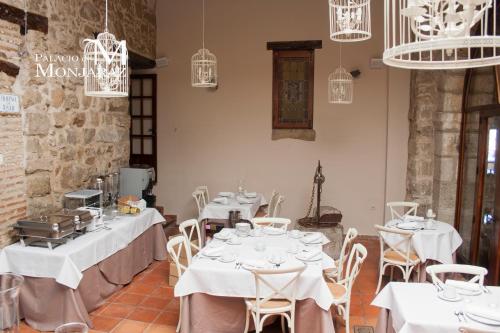 ein Restaurant mit weißen Tischen, Stühlen und Kronleuchtern in der Unterkunft Palacio de Monjaraz in Avila