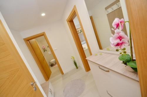 a bathroom with two mirrors and a vase with flowers on a counter at Nikola Lux apartments in Muo
