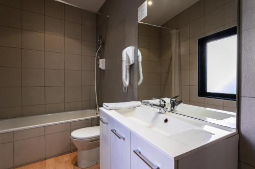 a bathroom with a sink and a toilet and a window at Hôtel Héliot, Cosy Places by Charme & Caractère in Toulouse