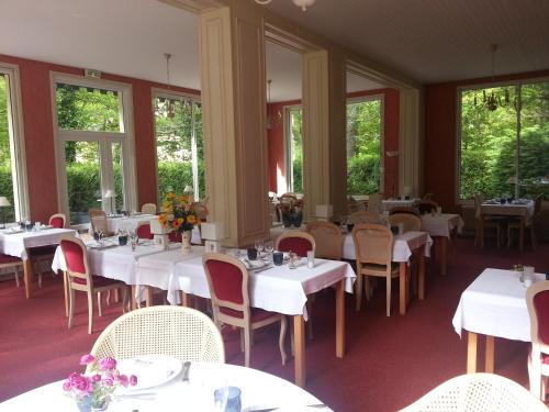 un comedor con mesas y sillas blancas y ventanas en Le Tronçais, en Saint-Bonnet-Tronçais