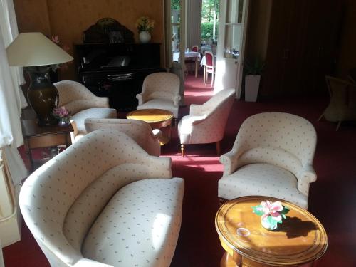 a living room with chairs and a table and a piano at Le Tronçais in Saint-Bonnet-Tronçais