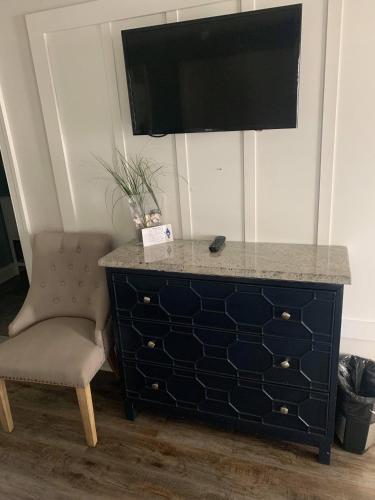 a black dresser with a chair and a television on top at Ocean Manor 1100 Inn in Ocean City