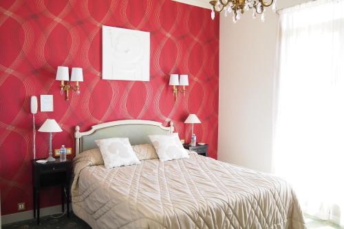 a bedroom with a large bed with red walls at Hôtel Primavera in Saint-Palais-sur-Mer