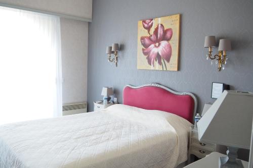 a bedroom with a white bed and a pink headboard at Hôtel Primavera in Saint-Palais-sur-Mer