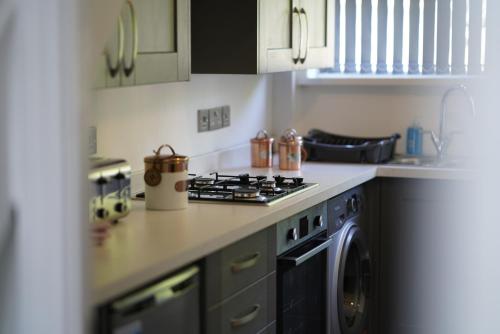 a kitchen with a stove and a washing machine at Risca Retreat in Risca
