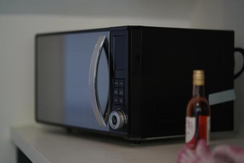 a bottle of beer sitting next to a microwave at Risca Retreat in Risca