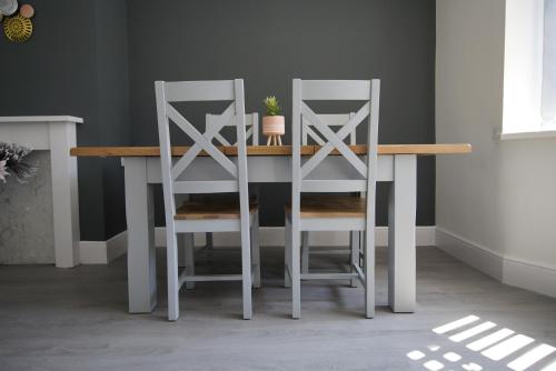 a dining room table with two white chairs around it at Risca Retreat in Risca