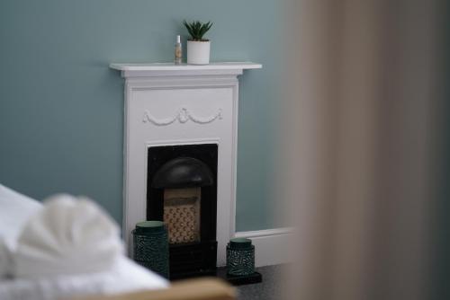 a white fireplace with a plant on top of it at Risca Retreat in Risca