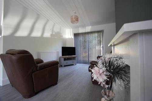 a living room with a couch and a chair and a television at Risca Retreat in Risca