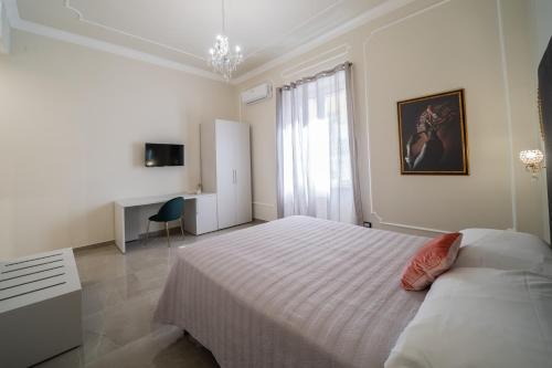 a white bedroom with a large bed and a desk at Amaris in Palermo