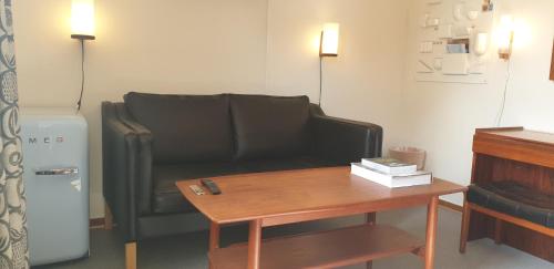 a living room with a black couch and a table at Hotell Hanöbris på Kivik in Kivik
