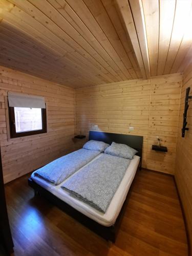 a bedroom with a bed in a wooden room at Barumi-Bungalow Leonardo in Porlezza