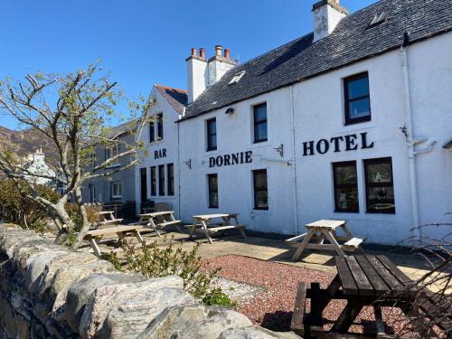 un edificio blanco con mesas de picnic delante en The Dornie, en Dornie