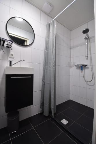 a bathroom with a shower with a sink and a mirror at 't zeeuwse achteruusje in Sint Annaland