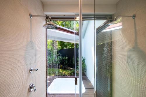 a bathroom with a shower and a bath tub at Pumilio Mountain & Ocean Hotel in Jacó