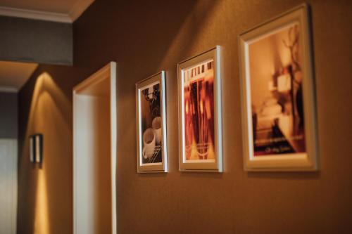 a group of framed pictures on a wall at Hotel de France Wiesbaden City in Wiesbaden