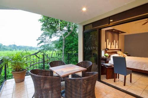a room with a bed and a table and chairs at Pumilio Mountain & Ocean Hotel in Jacó