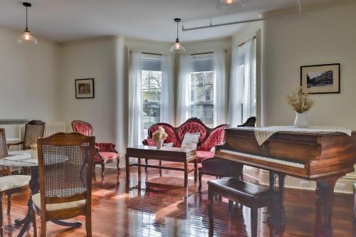 a living room with a piano and a table and chairs at The Burrell House in Keene
