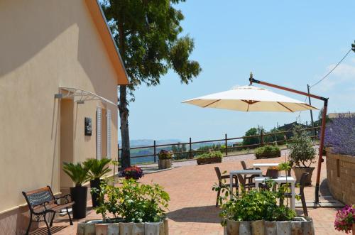 a patio with tables and chairs and an umbrella at RE UMBERTO b&b - Suite di charme e Country rooms in San Salvo