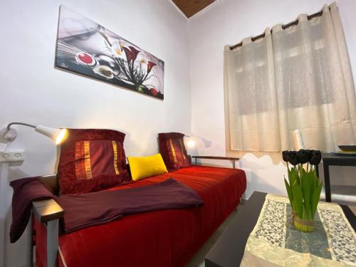 a bedroom with a red bed and a table with a lamp at Old Town Guest House in Beer Sheva