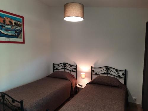 a bedroom with two beds and a light on the wall at Les Jardins De Santa Giulia - Charmante chambre dhte in Porto-Vecchio