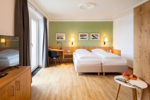 a hotel room with two beds and a desk at Hotel Seehof in Immenstaad am Bodensee
