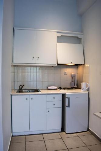 a kitchen with white cabinets and a sink at Kiki's Apartments in Néos Pírgos