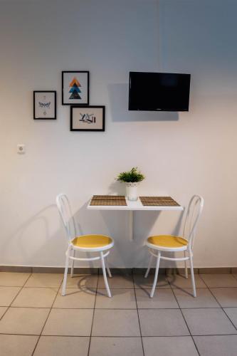 a table with two chairs and a tv on a wall at Kiki's Apartments in Néos Pírgos