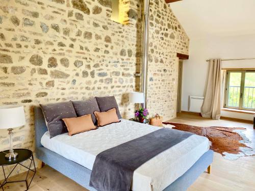 a bedroom with a large bed with a stone wall at Maison du Cocher in Cluny