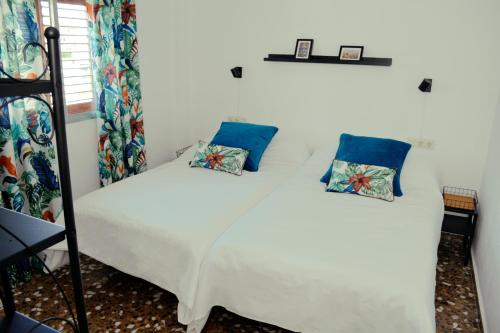 sypialnia z białym łóżkiem z niebieskimi poduszkami w obiekcie Los Olivos w mieście Chiva