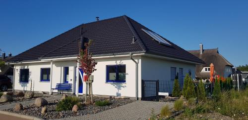 ein kleines weißes Haus mit schwarzem Dach in der Unterkunft Haus Kliffblick in Glowe