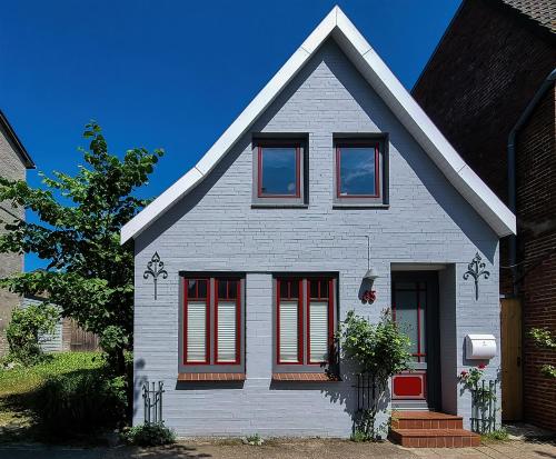 a white house with red shutters on it at Gemütliches Ferienhaus - ankommen und wohlfühlen in Husum