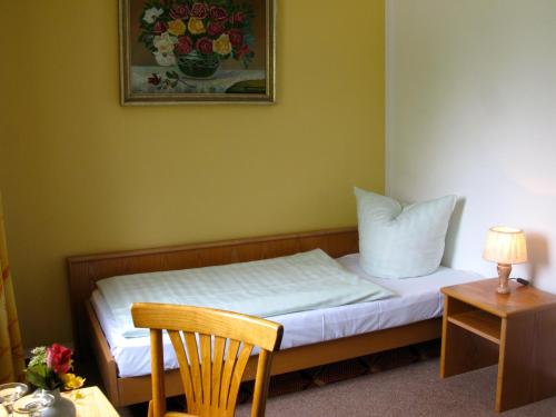 ein kleines Schlafzimmer mit einem Bett mit einem Bild an der Wand in der Unterkunft Landhotel Goldener Becher in Limbach - Oberfrohna