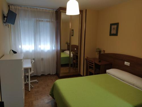 a bedroom with a bed and a desk and a mirror at Hotel Camagüey in Gijón