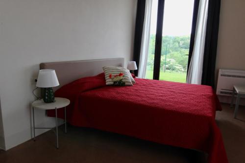 sypialnia z czerwonym łóżkiem i oknem w obiekcie Relais Mevigo - Casa Padronale w mieście Casola Valsenio