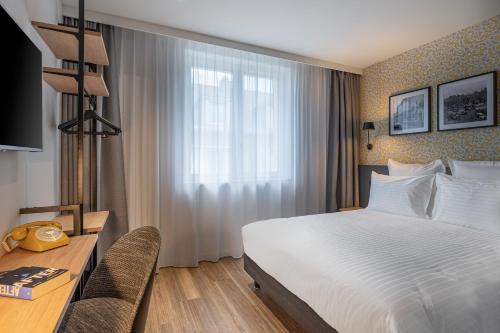 a hotel room with a bed and a desk and a window at Ferdinand Hotel Tours in Tours