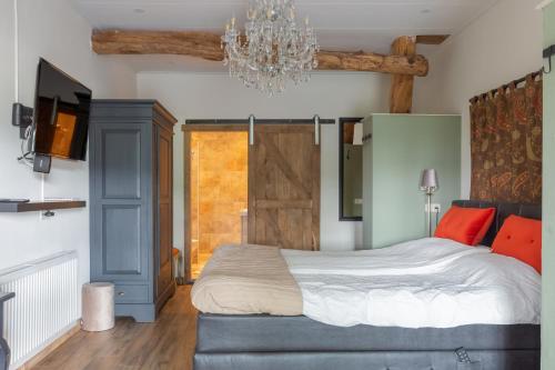 a bedroom with a large bed and a chandelier at Bed and Breakfast De Boerderij Kamer in Nutter