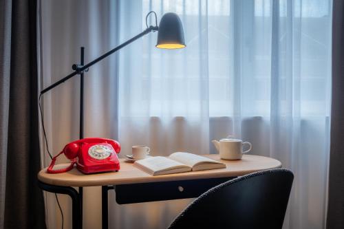 a table with a red bag and a book and a lamp at Ferdinand Hotel Tours in Tours