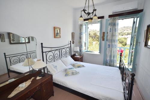 a bedroom with a bed and two windows and a table at Traditional house by the sea in Mandrakion