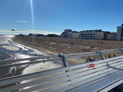 a view of a beach with a bench and people at Ann Apartments opposite the Pier with sea view in Portsmouth