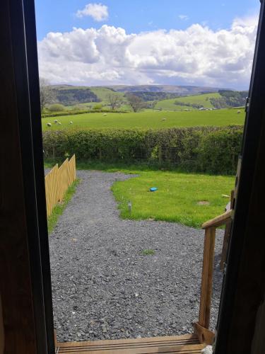 a door open to a view of a field of sheep at Y Cwtch in Trefeglwys