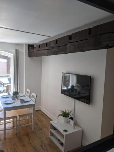a living room with a table and a tv on a wall at Riverside Apartment York in York