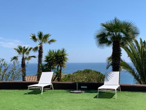 two white chairs sitting on a lawn with palm trees at Sitges Spaces Sea View Villa- 6 Bedrooms, 5 bathrooms, 2 private pools, Near center in Sitges