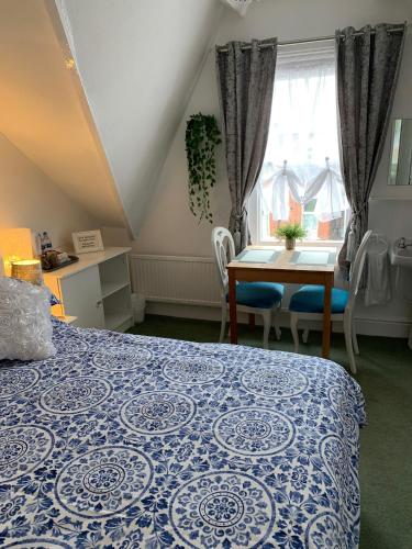 a bedroom with a blue and white bed and a table at The George Guest House in Bridlington