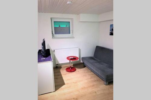 a living room with a couch and a red stool at Gehobene Studentenwohnung in Allensbach