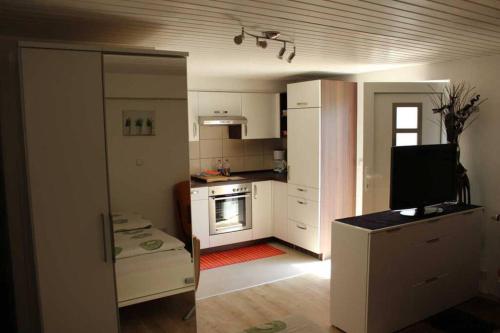 a kitchen with white cabinets and a flat screen tv at Gehobene Studentenwohnung in Allensbach