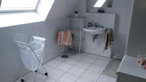 a white bathroom with a sink and a chair at München großzügige Wohnung sehr ruhig in Munich