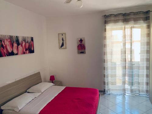 um quarto com uma cama com um cobertor vermelho e uma janela em Casa Sofia em Sorrento